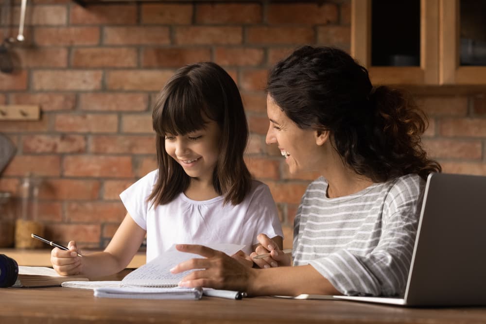 Mother and daughter successfully learning together at the kitchen table